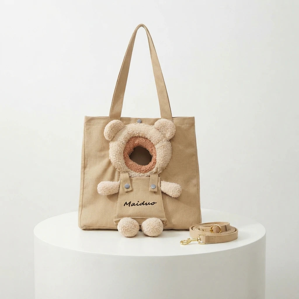 Khaki canvas tote-style cat carrier with a teddy-bear head opening, displayed on a white round pedestal