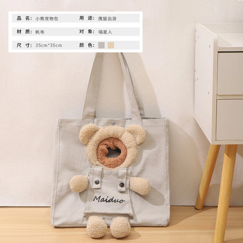 Light grey canvas tote-style cat carrier with a teddy-bear head opening beside a white drawer unit, with a spec chart in the corner